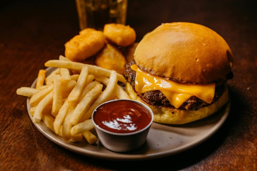 Tasty cheeseburger served with french fries, nuggets, and dipping sauce on a plate.